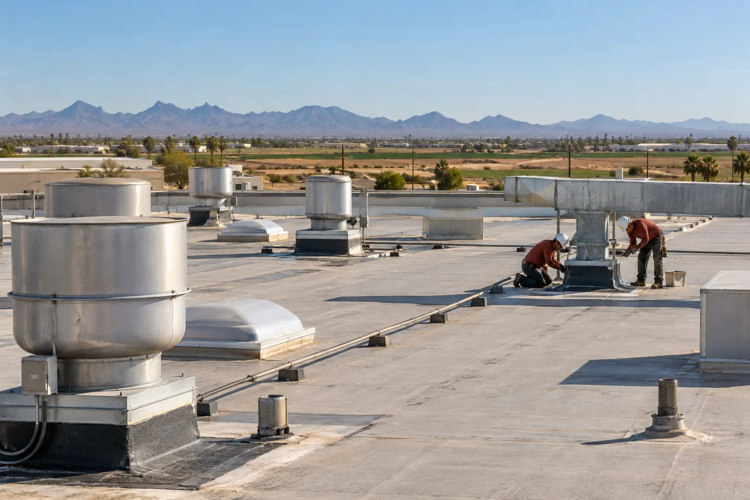 Roofers sealing a curb near exhaust stacks on an industrial roof