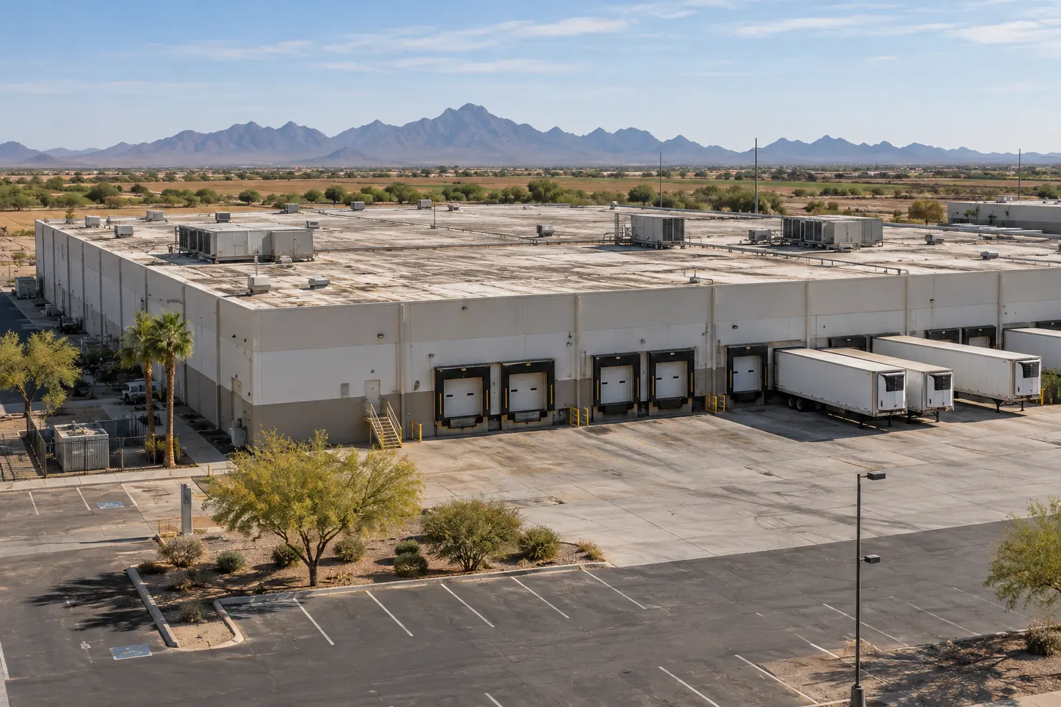 Aged distribution warehouse with truck docks and rooftop units on a large flat roof